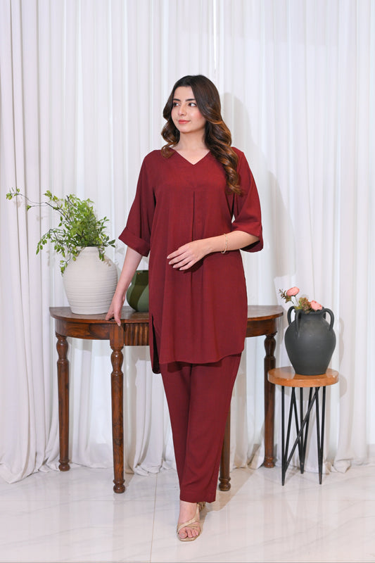Woman in a red outfit standing in a room with white curtains and decorative items.